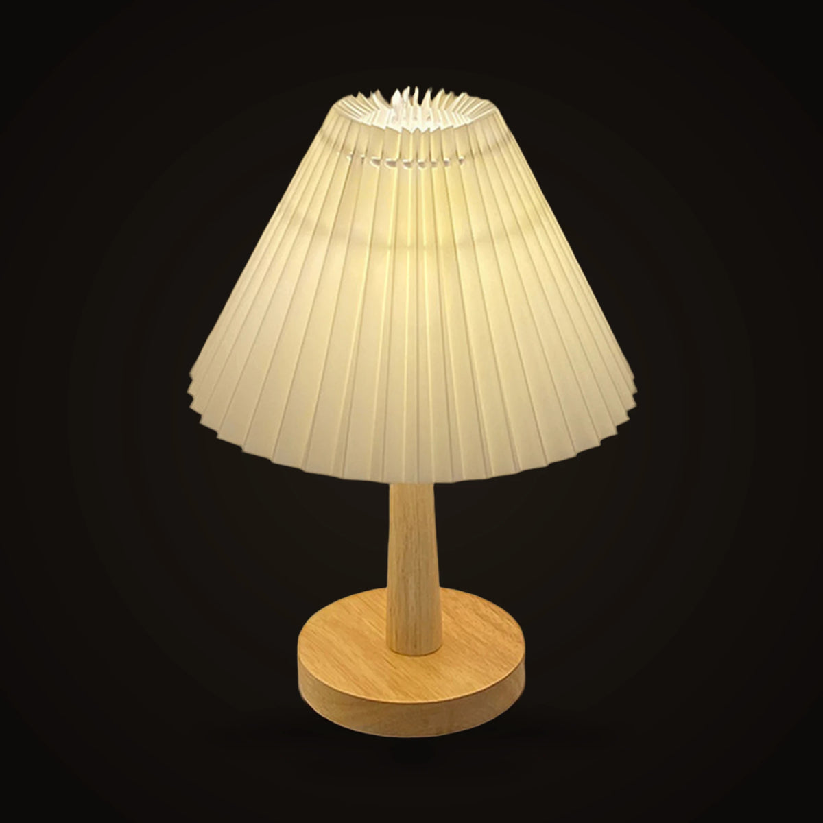 The Lumivano Pleat on the dark brand ground: a wide cone of off-white pleated fabric gathered into sharp vertical folds, lit from inside, on a tapered pale wooden stem and a round wooden foot.