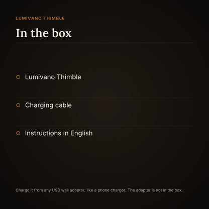 An in-the-box card for the Lumivano Thimble on the dark brand ground: the lamp, a charging cable and instructions in English, with a note that it charges from any USB wall adapter like a phone charger, and that the adapter is not in the box.