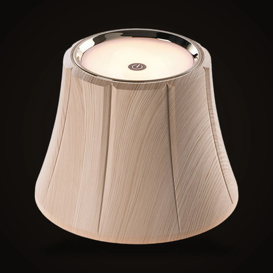 The Lumivano Vintner on the dark brand ground: a small bell-shaped lamp shade in pale faux wood grain with soft vertical seams, a polished chrome ring at its top edge around a flat glowing disc with a small round power symbol in the middle.
