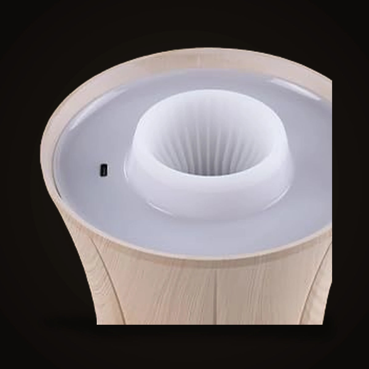 A view into the underside of the Lumivano Vintner on the dark brand ground, showing the ribbed white silicone funnel that grips the neck of a bottle, with the small charging port on the rim beside it.
